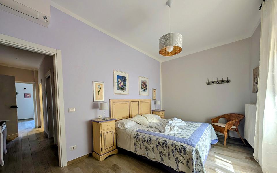 Camera accogliente con letto matrimoniale, luce naturale, arredi in legno e decorazioni floreali.