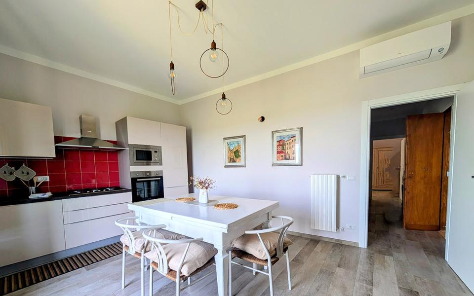 Cucina luminosa con tavolo bianco, sedie accoglienti e pareti dai colori caldi.