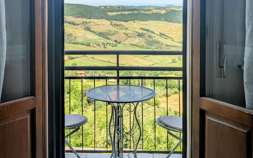 Vista su colline verdi da un balcone con tavolino, atmosfera di pace e serenità.